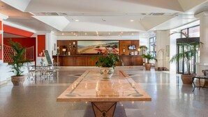 A spacious lobby with a reception desk, a large painting, and potted plants. - Resort Marina di Castello Golf & SPA (Castel Volturno)