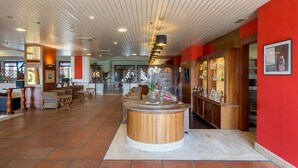 A spacious lobby with a central wooden bar, seating areas, and a red accent wall. - Resort Marina di Castello Golf & SPA (Castel Volturno)