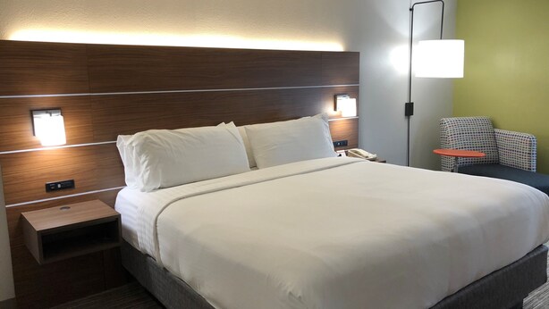A hotel room with a large bed, bedside tables, a nightstand, a lamp, and a chair. - Holiday Inn Express Atlanta-Stone Mountain by IHG (Stone Mountain)