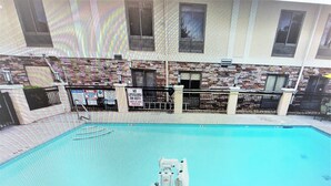 An indoor swimming pool with a lifeguard stand, a diving board, and a pool ladder. - Holiday Inn Express Atlanta-Stone Mountain by IHG (Stone Mountain)