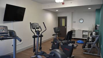 Una palestra con macchinari cardio, manubri e un televisore.