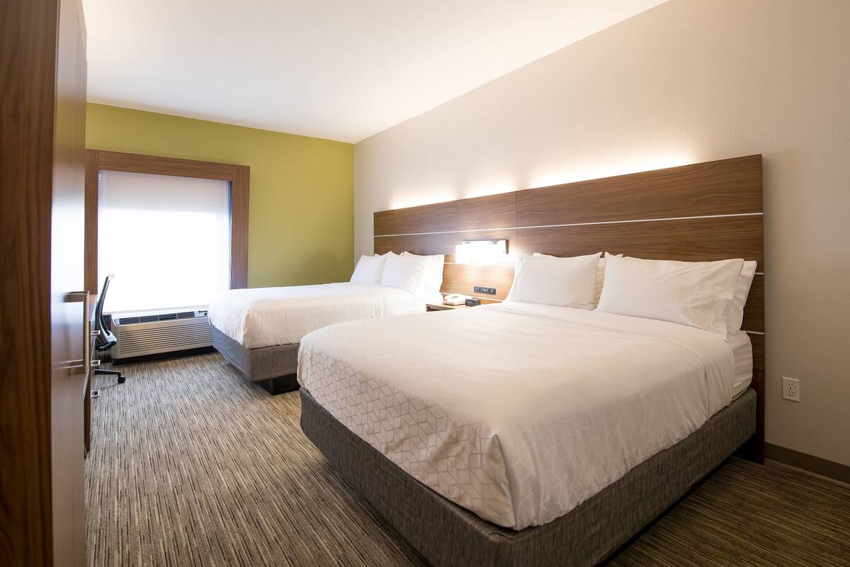 A hotel room with two beds, a desk, and a chair.