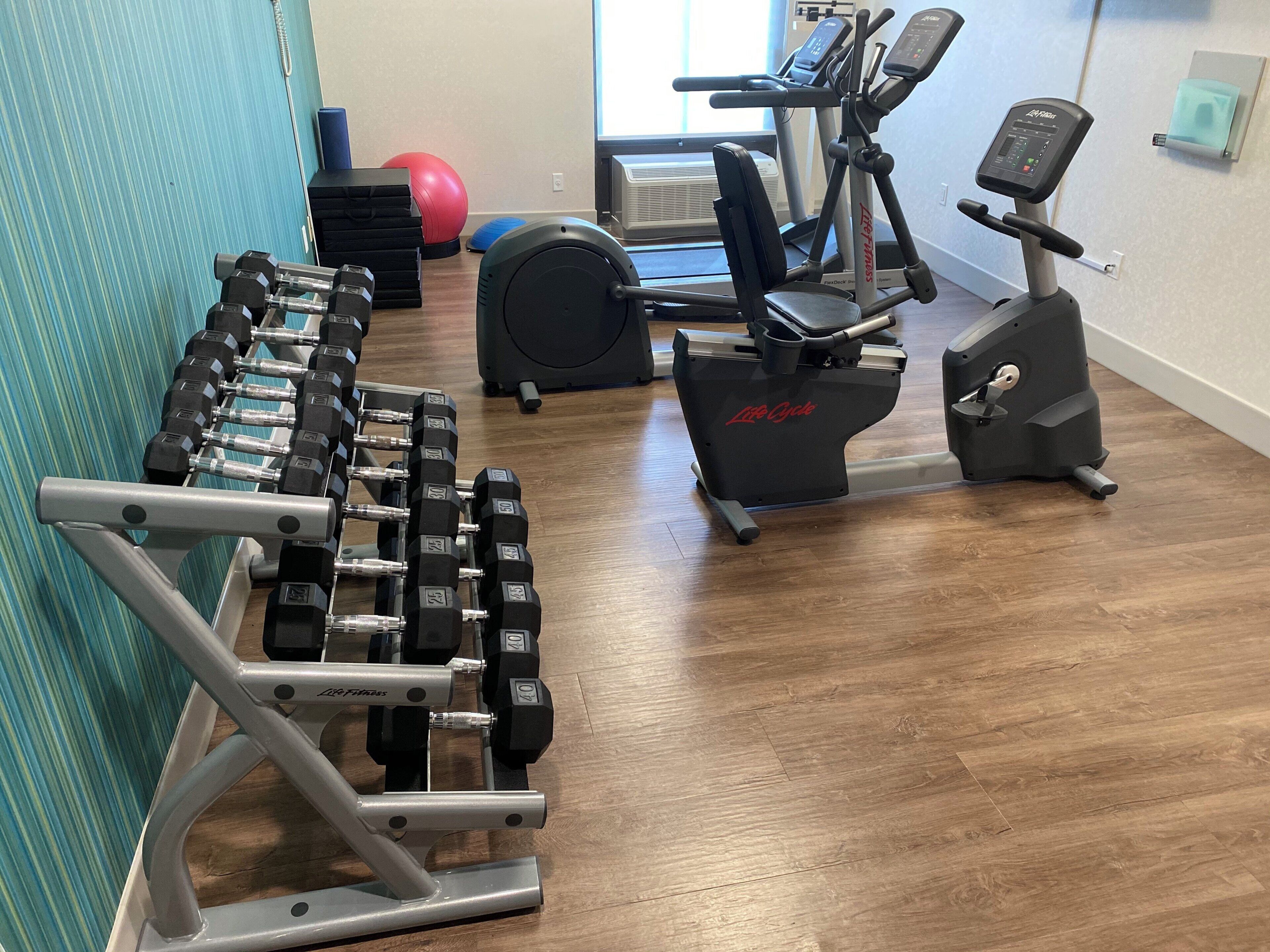 A home gym with a dumbbell rack, an elliptical, and a stationary bike.