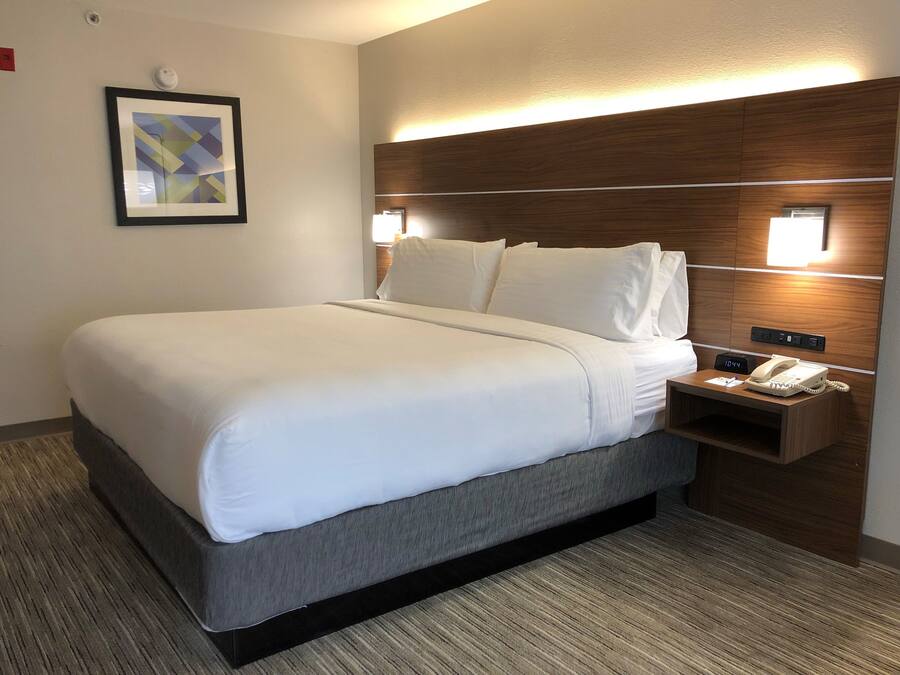 Une chambre d’hôtel avec un grand lit, une table de chevet avec un téléphone et une lampe fixée au mur.