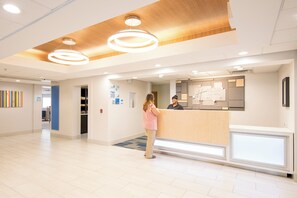 A hotel reception area with a wooden ceiling, a reception desk, and a blue wall with a sign. - Holiday Inn Express Atlanta-Stone Mountain by IHG (Stone Mountain)