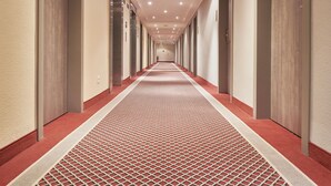 A long, narrow hotel corridor with a patterned carpet and doors on both sides. - Best Western Hotel Leipzig City Center (Leipzig)