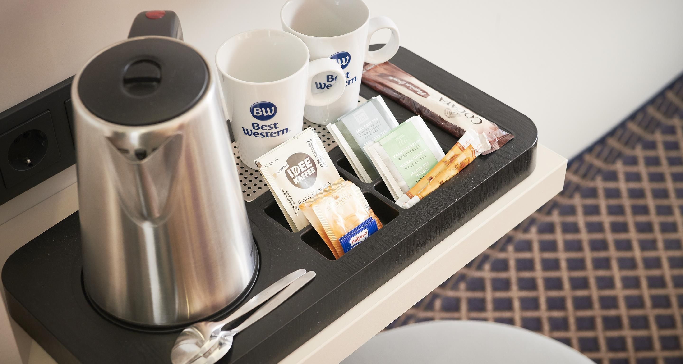 A tray with a coffee pot, two mugs, and various tea packets.