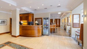 A hotel lobby with a reception desk, a refrigerator stocked with beverages, and a seating area with tables and chairs. - Best Western Hotel Leipzig City Center (Leipzig)