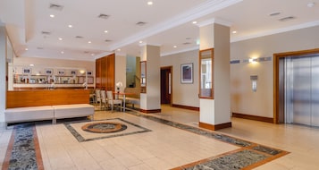Un vestíbulo de hotel con mostrador de recepción, zona de estar y ascensor.