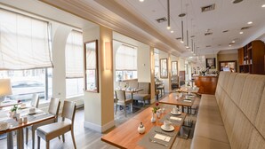 A modern restaurant with long communal tables, cushioned seating, and a bar area. - Best Western Hotel Leipzig City Center (Leipzig)