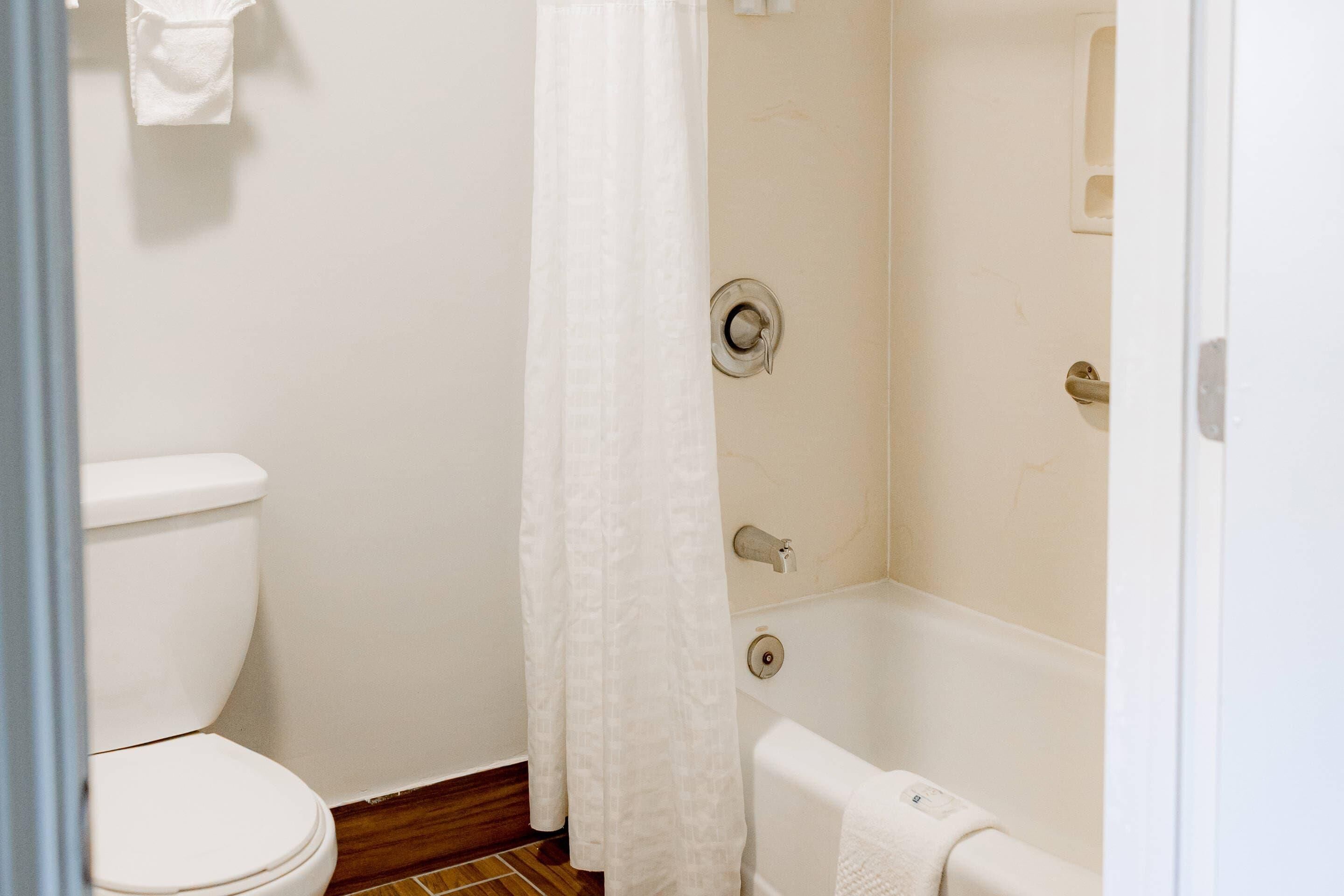 Un baño con inodoro, bañera y cortina de ducha.