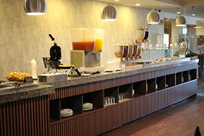 A buffet setup with a coffee machine, juice dispenser, and various food containers. - Four Points by Sheraton Saltillo (Saltillo)