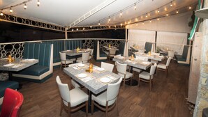 A restaurant with booths and tables, string lights, and a stone wall. - Four Points by Sheraton Saltillo (Saltillo)