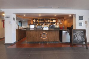 A reception area with a wooden counter, a refrigerator, and a sign promoting local American wheat beer. - Four Points by Sheraton Saltillo (Saltillo)
