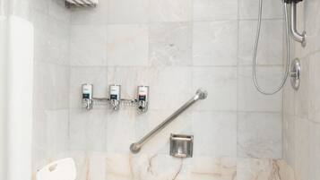 A modern shower area with a handheld showerhead, a grab bar, and a white chair.