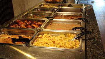 Un bufé con diversas opciones de comida, incluyendo huevos revueltos, pollo y otros platos.