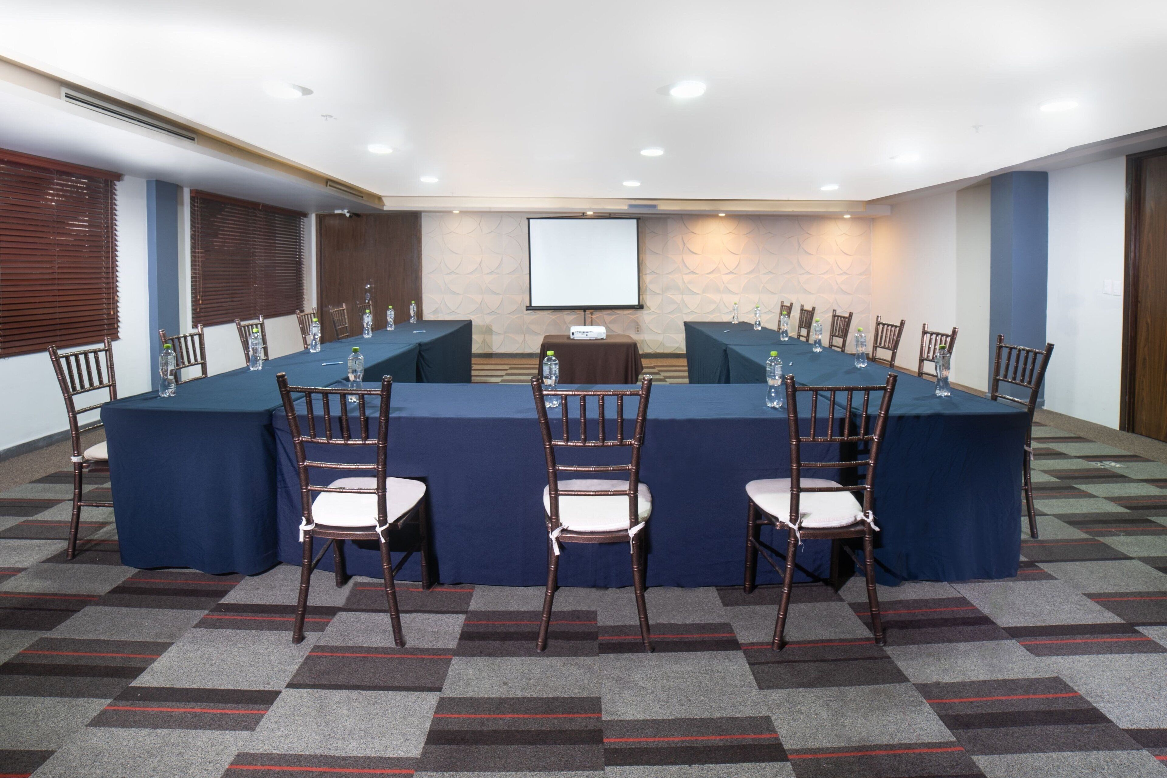 A conference room with a long table, chairs, and a projector screen.
