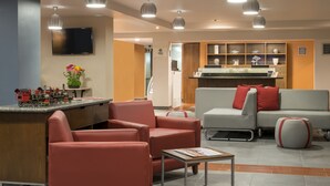 A modern hotel lobby with a reception desk, seating area, and a television mounted on the wall. - Four Points by Sheraton Saltillo (Saltillo)