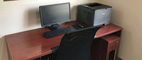 A wooden desk with a computer monitor, keyboard, and printer.