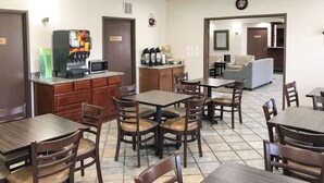 Un vestíbulo de hotel con una estación de café, zona de estar y una recepción.