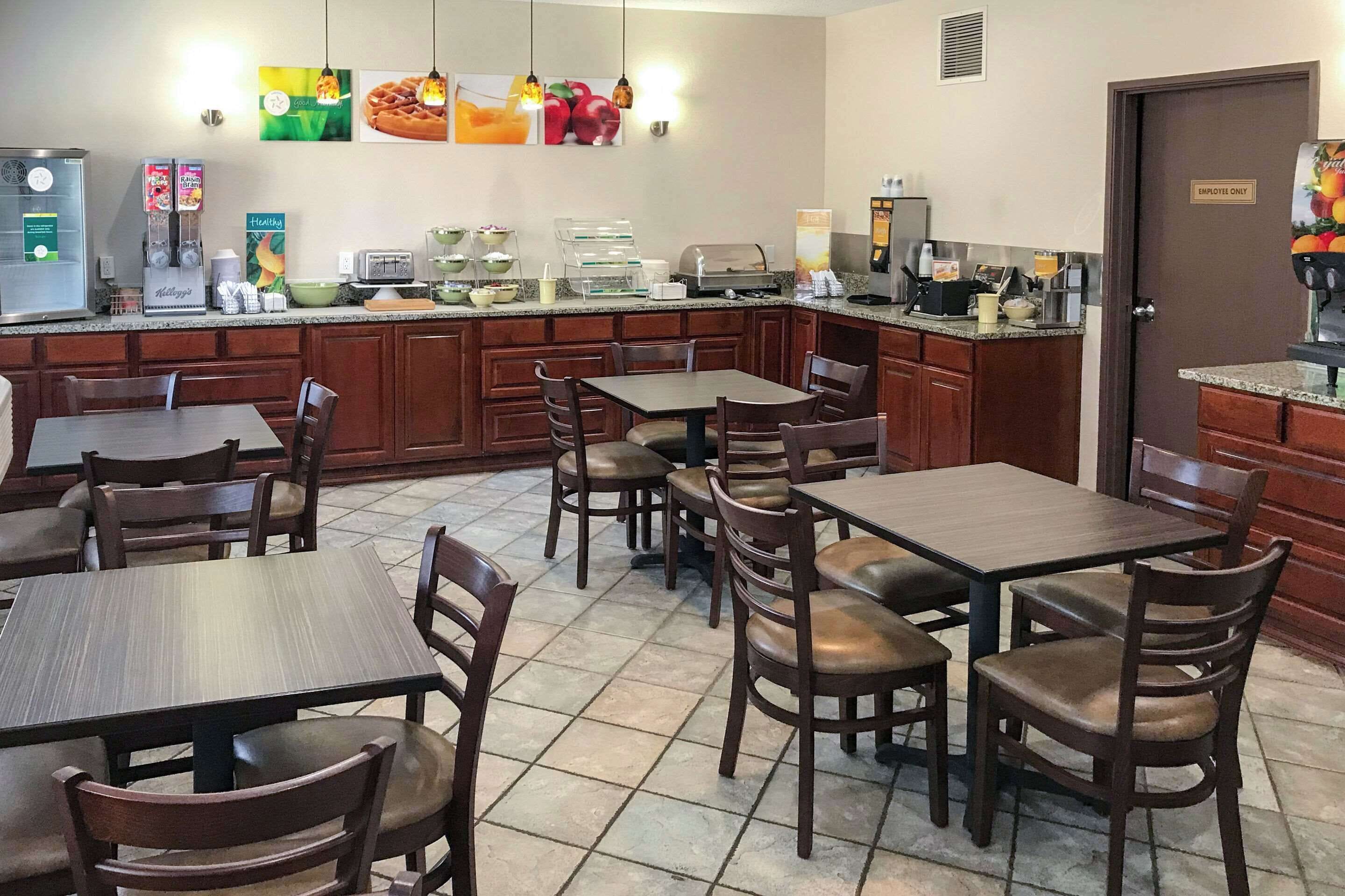 A restaurant with wooden tables and chairs, a coffee machine, and a refrigerator.