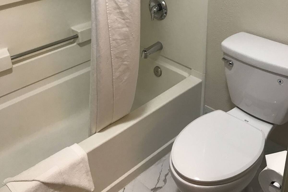 Een badkamer met een bad, toilet en douchegordijn.
