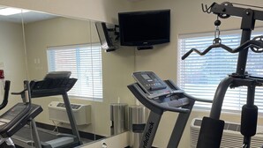 Un gimnasio con cintas de correr, una bicicleta estática y máquinas de pesas.