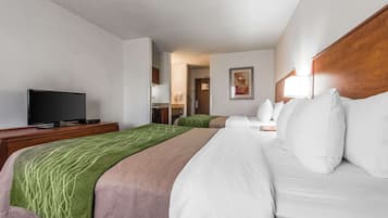 A hotel room with a bed, a TV on a stand, a wooden headboard, and a painting on the wall.