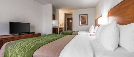 A hotel room with a bed, a TV on a stand, a wooden headboard, and a painting on the wall.