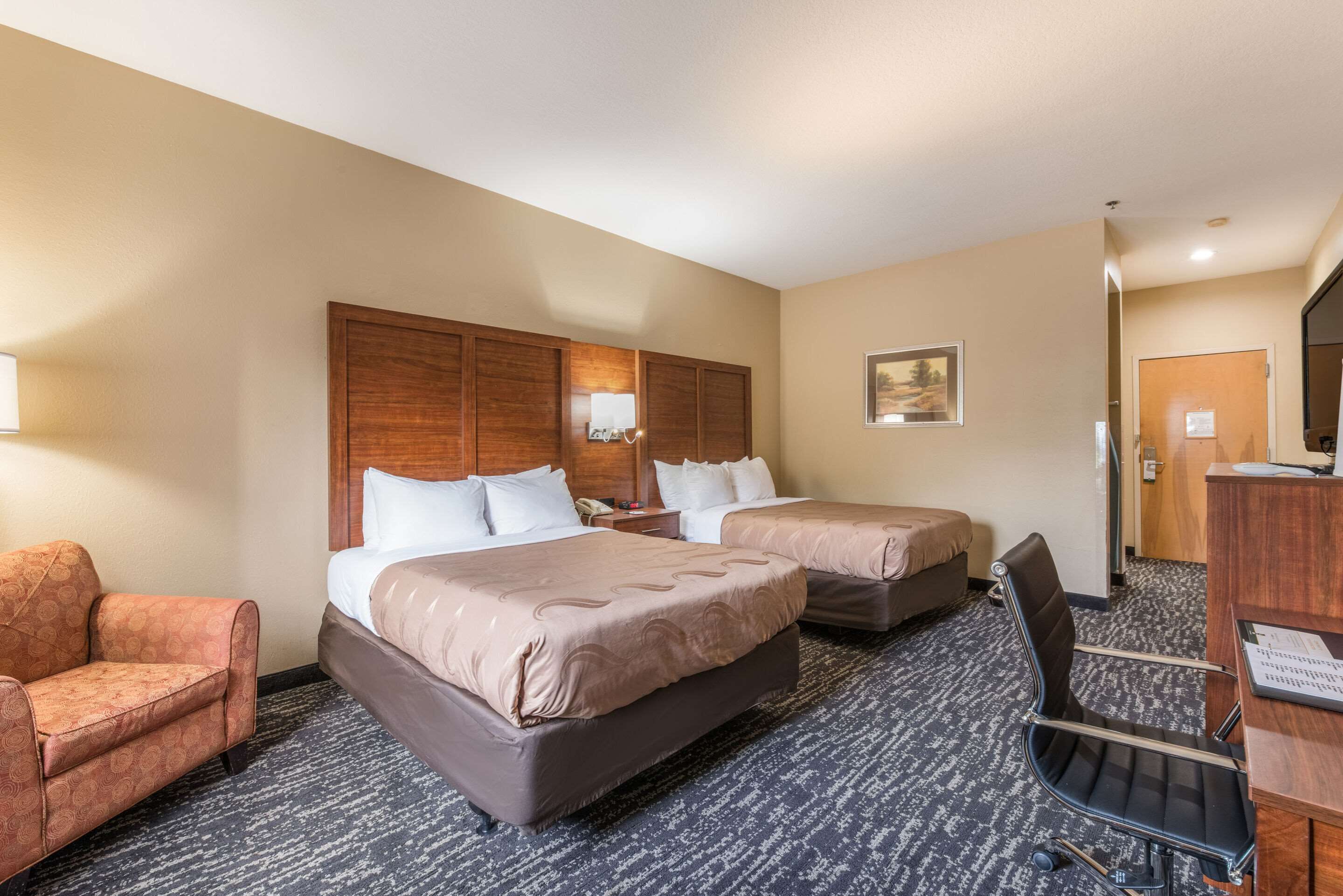 Una habitación de hotel con dos camas, un escritorio, una silla y un sofá.