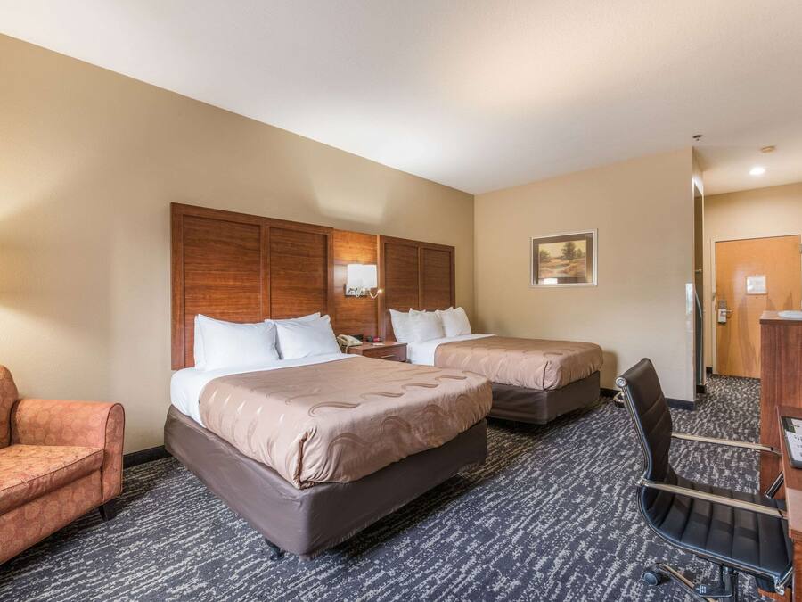 Una habitación de hotel con dos camas, un escritorio, una silla y un sofá.