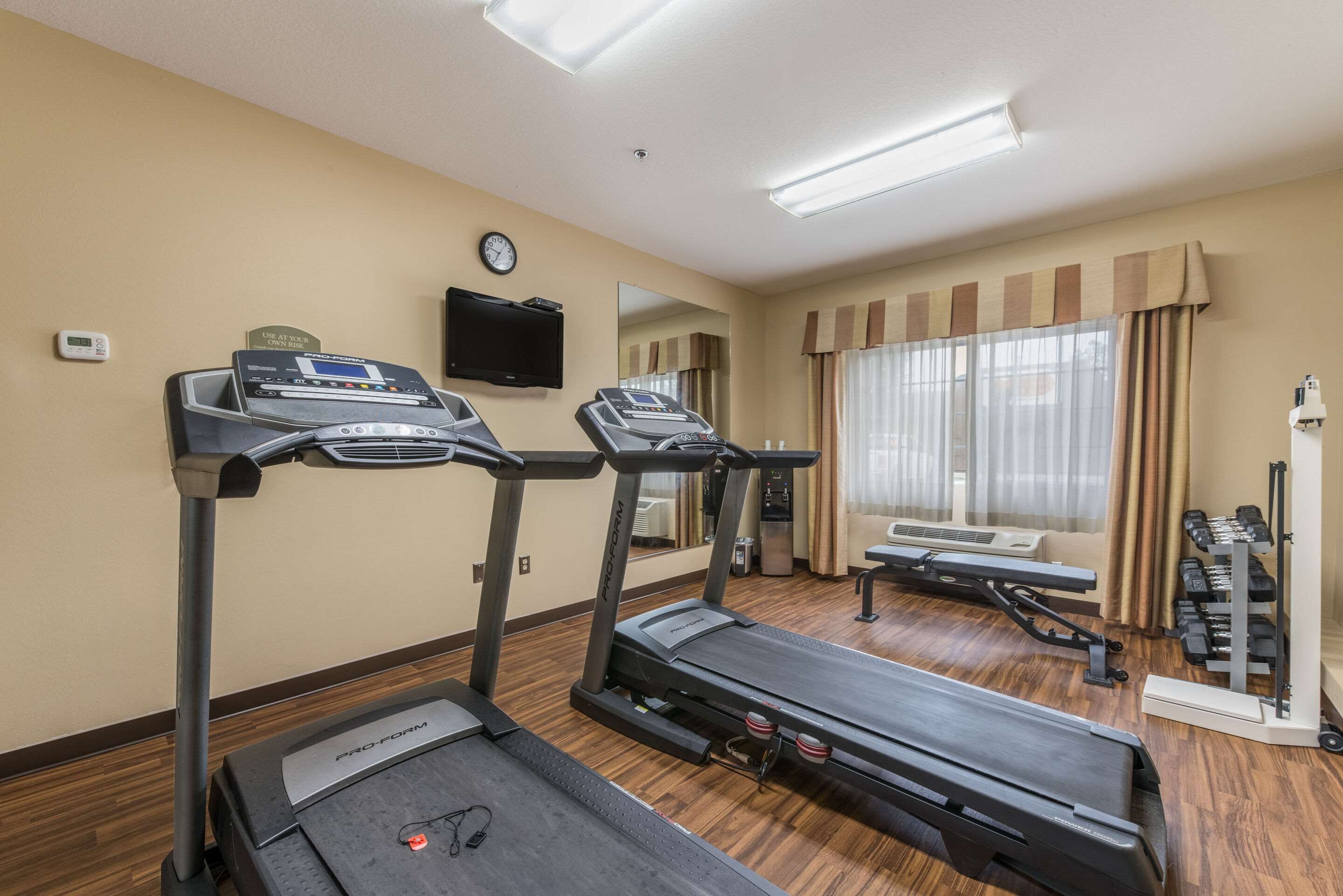 A hotel fitness room with treadmills, a bench, and a weight rack.
