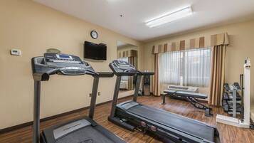 A hotel fitness room with treadmills, a bench, and a weight rack.