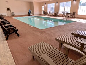 A swimming pool area with multiple lounge chairs and tables, a wheelchair-accessible chair, and a door marked "EXIT".