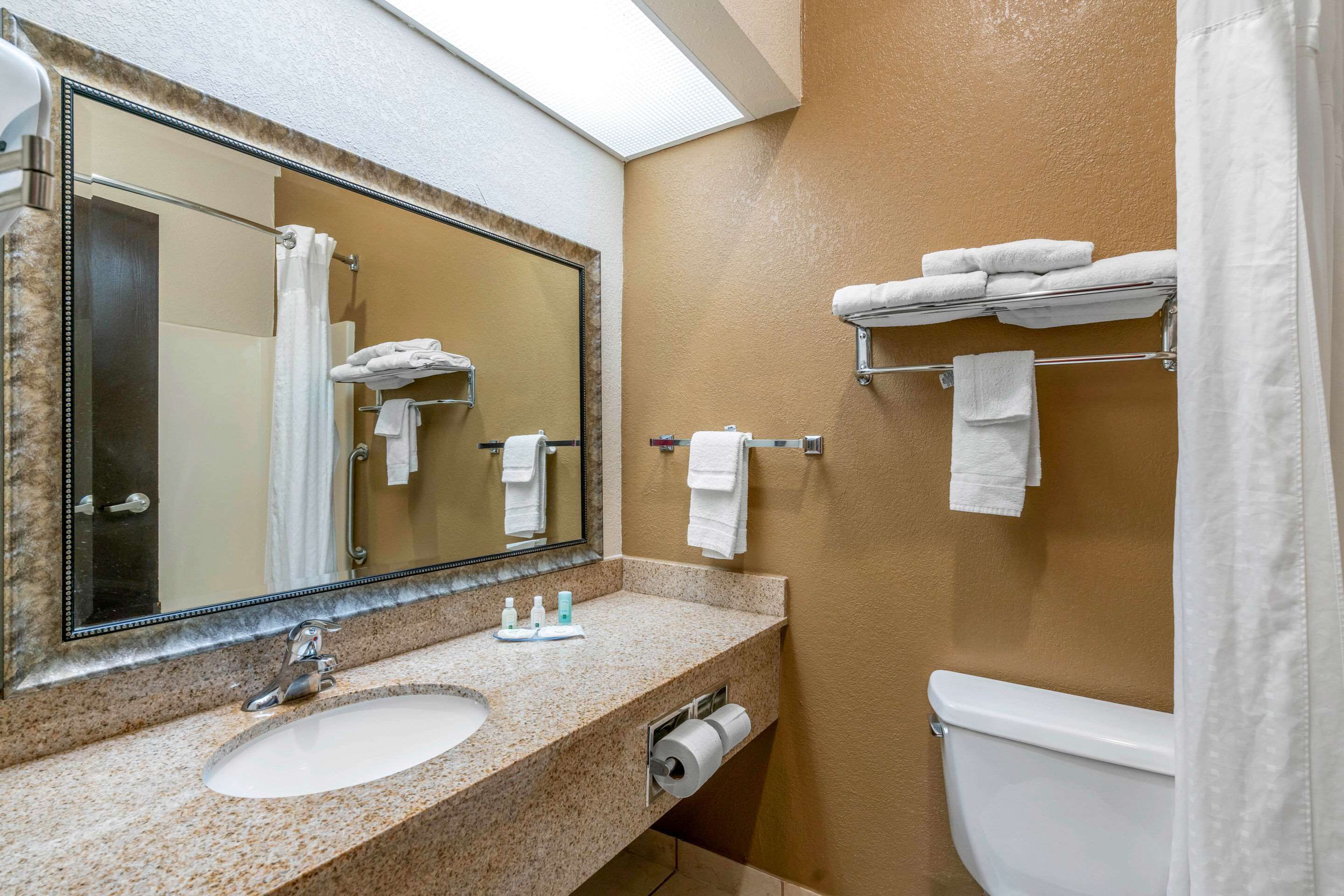 A bathroom with a sink, mirror, towel rack, and toilet.