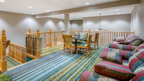 A spacious room with a wooden staircase, a sofa set, and a dining table with chairs. - Quality Inn & Suites Jefferson City (Jefferson City)