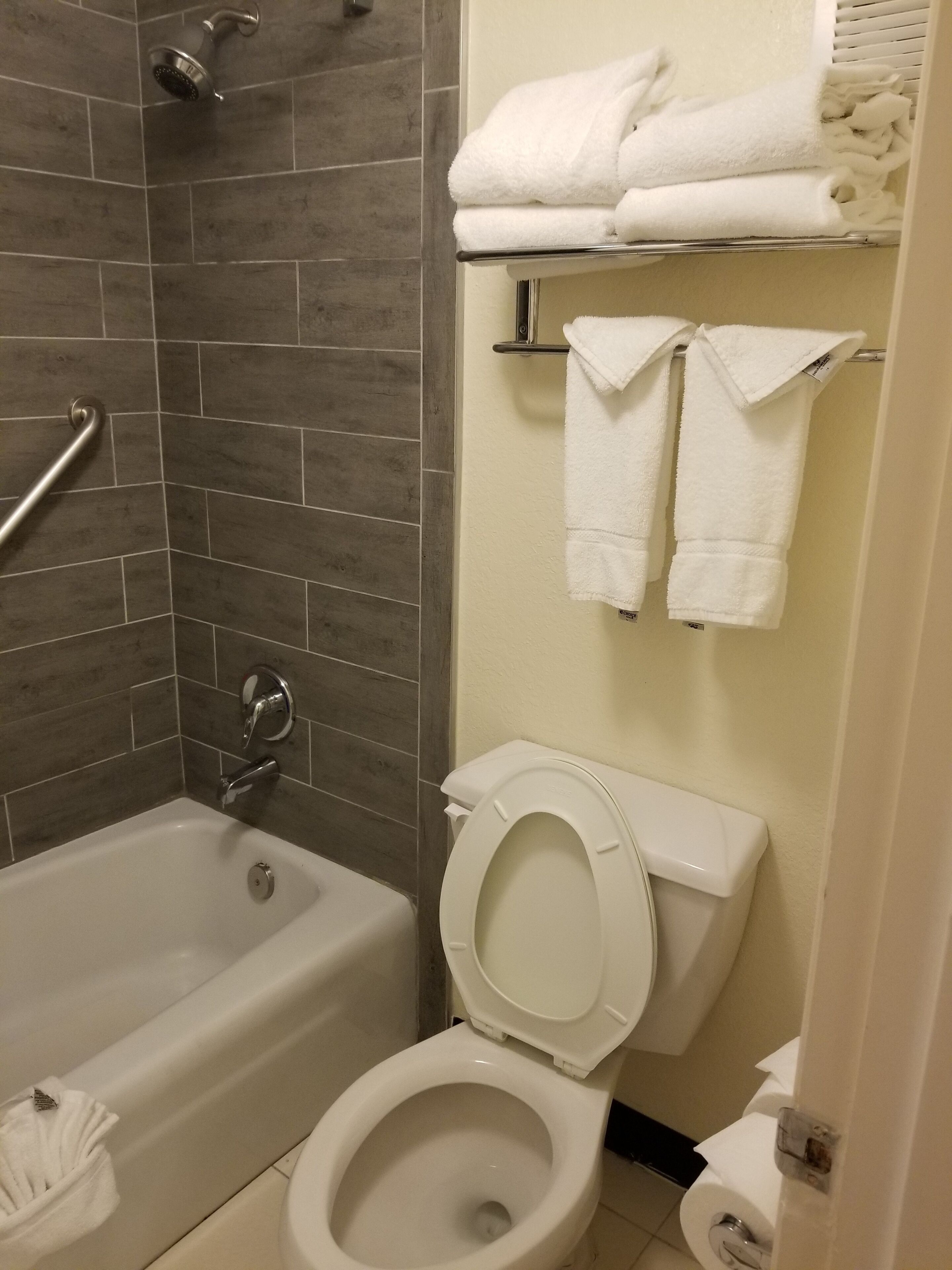 Un baño con bañera, inodoro y un perchero con toallas dobladas.