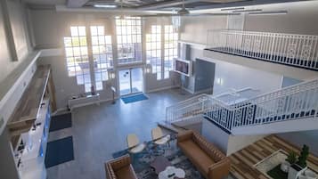 A spacious interior with a reception desk, seating area, staircase, and large windows.