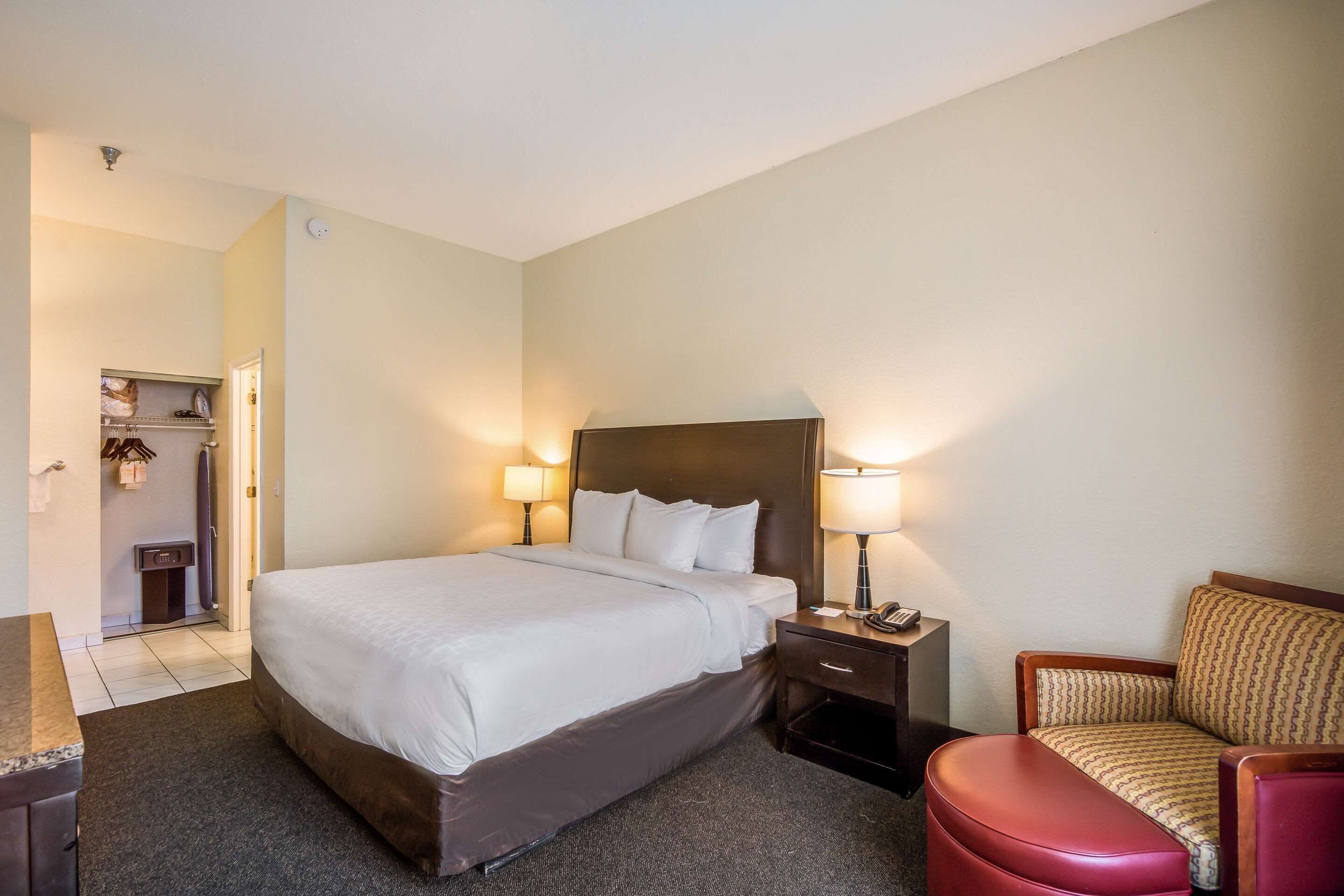 Een hotelkamer met een groot bed, nachtlampjes, een bureau en een stoel.