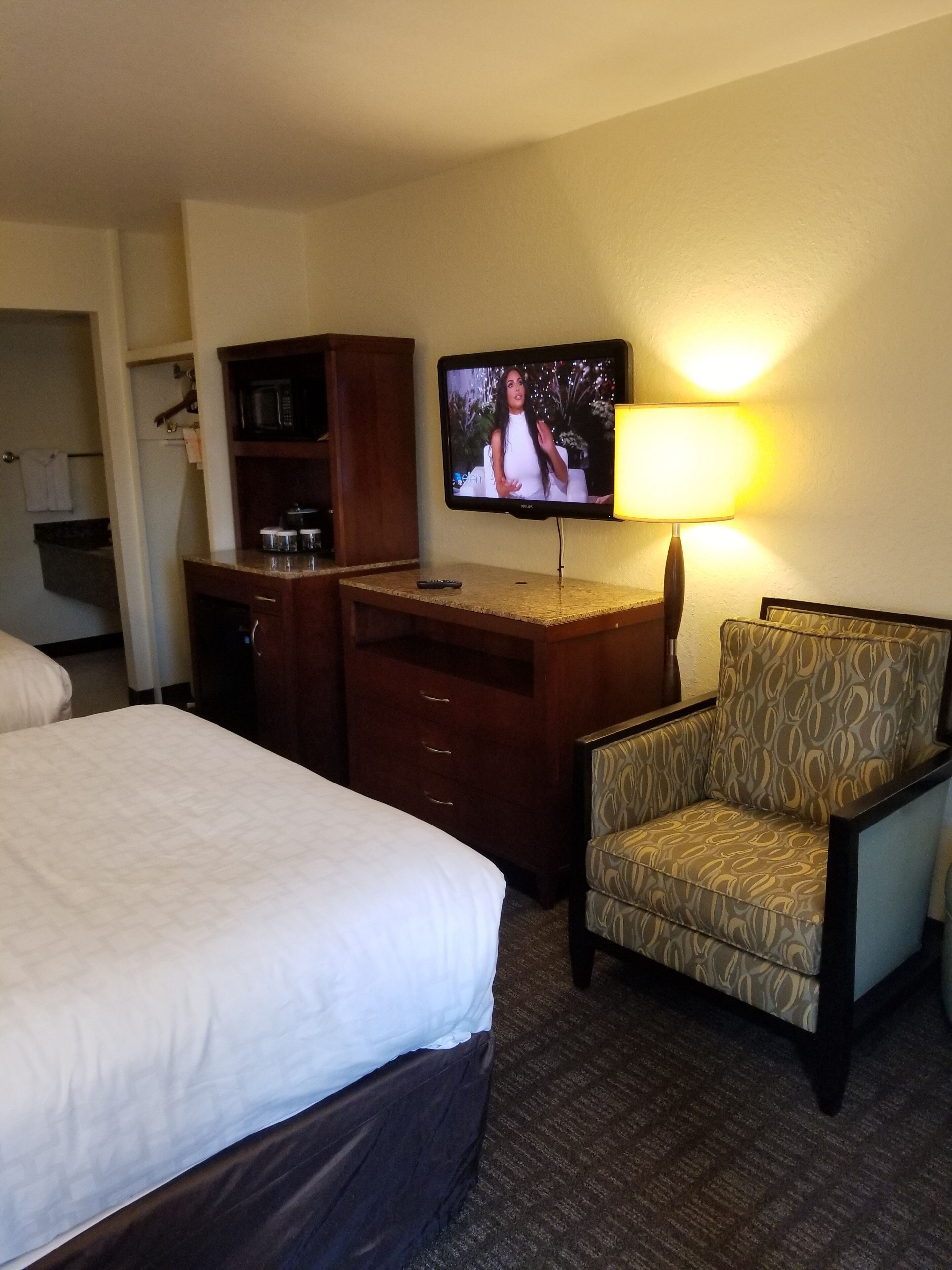Ein Hotelzimmer mit Bett, Schreibtisch, Fernseher, Stuhl und Lampe.
