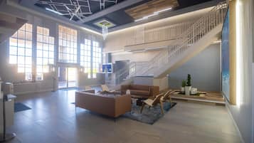 A spacious lobby with a staircase, seating area, and large windows.