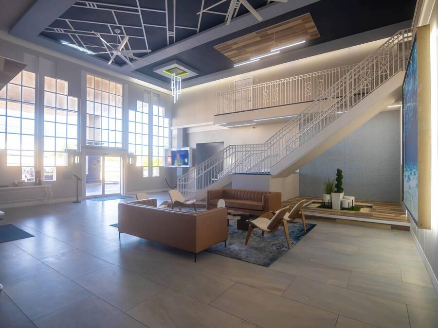 A spacious lobby with a staircase, seating area, and large windows.