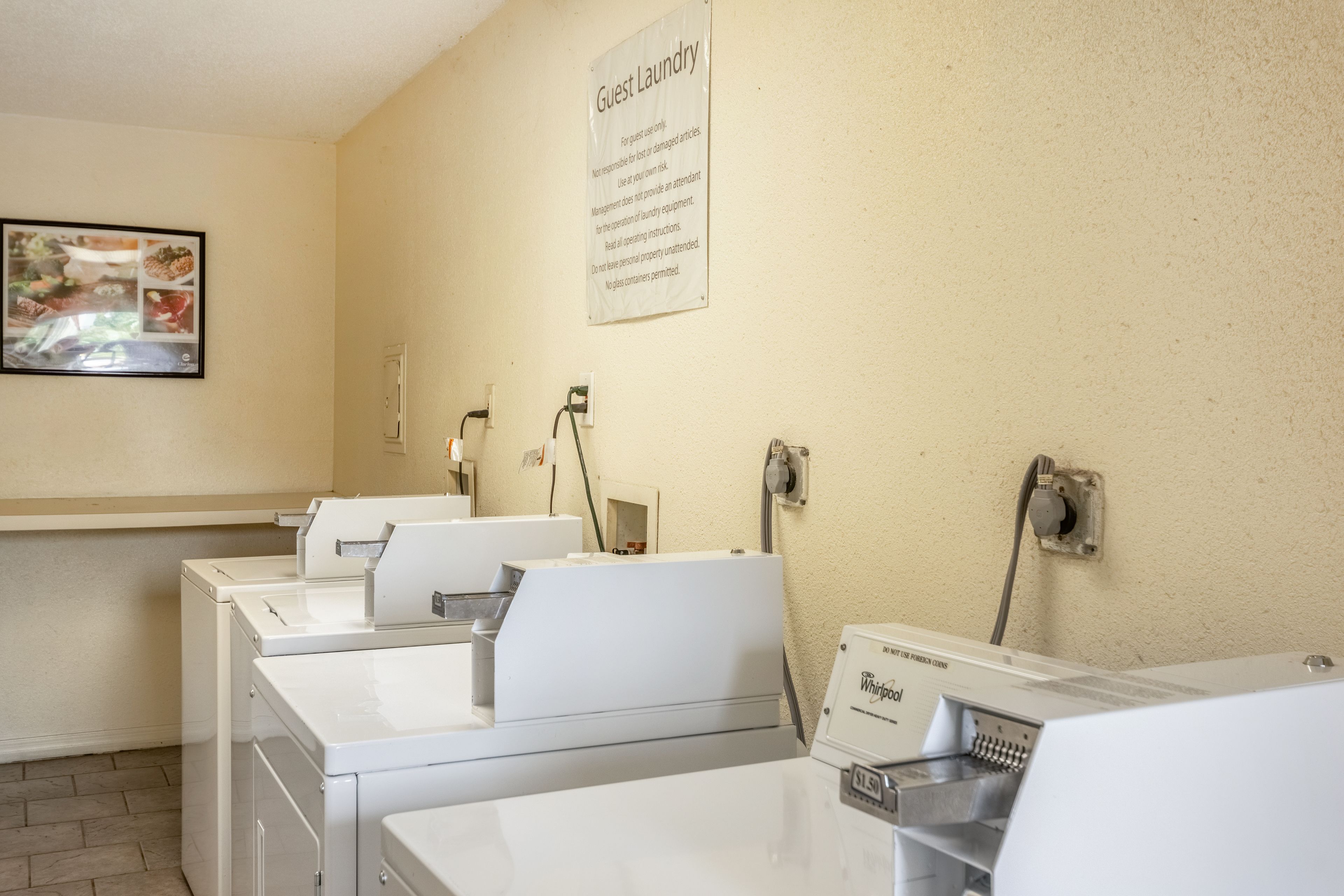 A laundry area with multiple washing machines and a sign indicating guest laundry services.