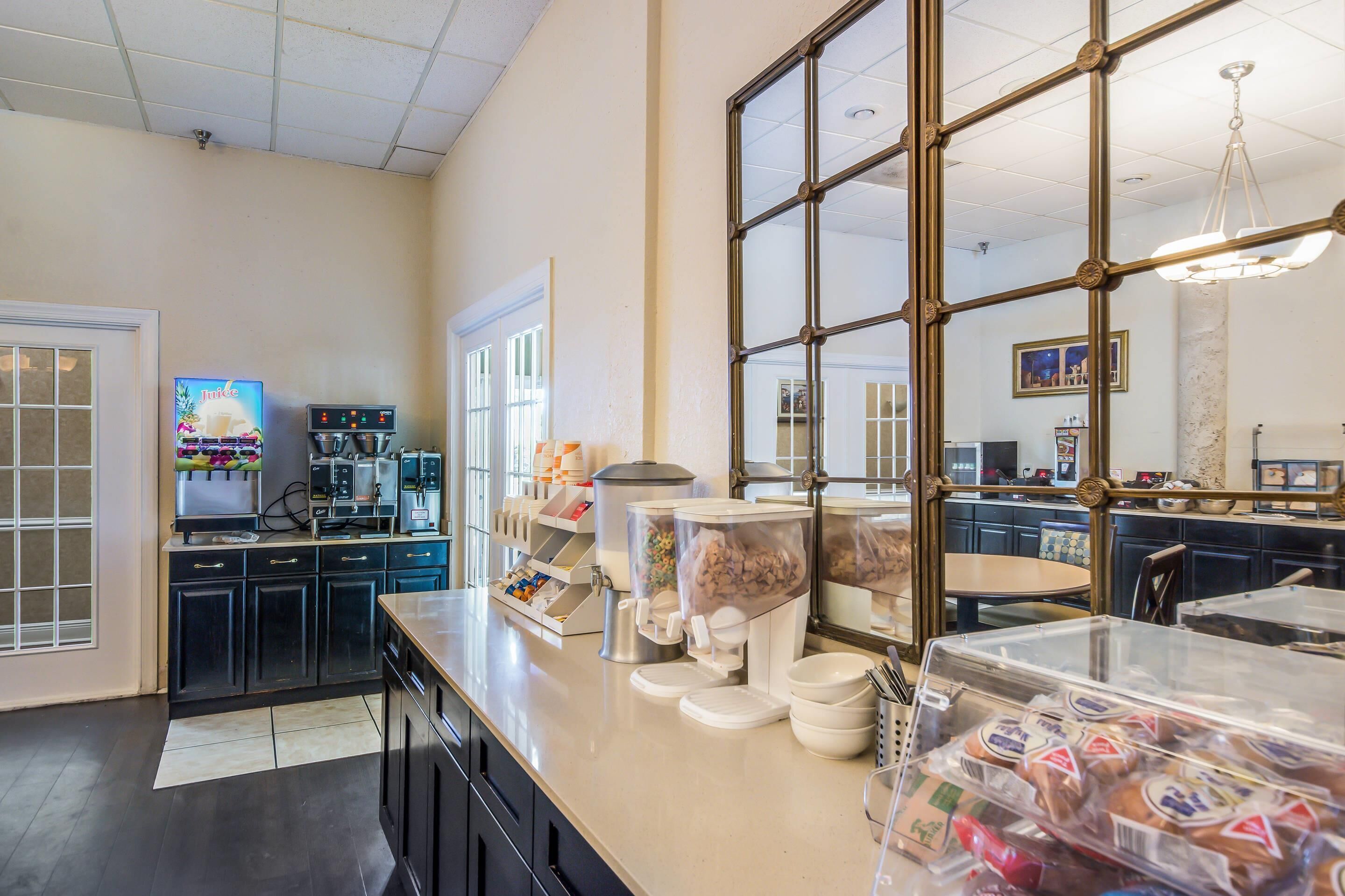 Una zona de cocina con cafetera, dispensadores de comida y un ventanal grande.