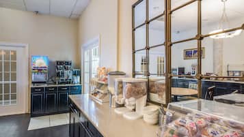 Una zona de cocina con cafetera, dispensadores de comida y un ventanal grande.