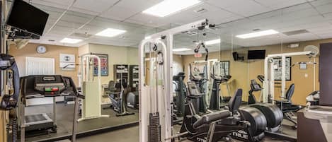 A gym with exercise equipment, a treadmill, and a mirrored wall.