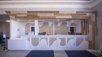 A reception desk with a modern design, a wooden ceiling, and a blue-lit wave pattern on the wall.