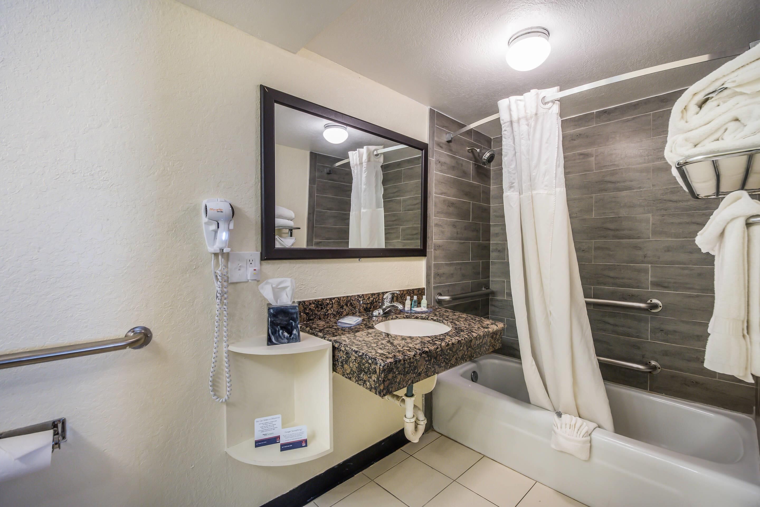 A bathroom with a sink, mirror, towel rack, and shower.