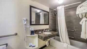 Un baño con lavamanos, espejo, toallero y ducha.
