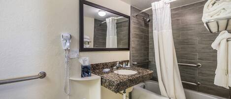 A bathroom with a sink, mirror, towel rack, and shower.